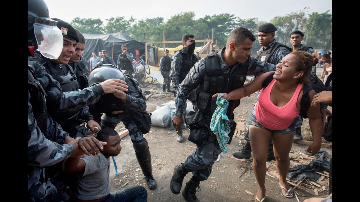 Policiais desocupando moradias ilegais, com o uso da força. Créditos: Revista IstoÉ via Youtube